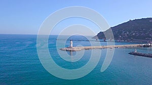 Lighthouse on background of seascape and coastal city. Clip. Top view of beautiful seascape with white lighthouse off