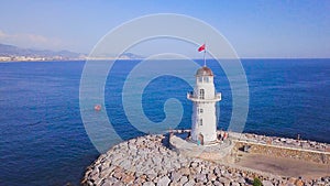 Lighthouse on background of seascape and coastal city. Clip. Top view of beautiful seascape with white lighthouse off