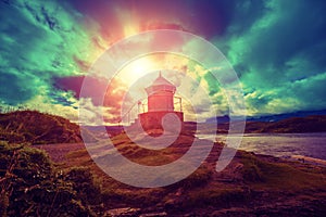 Lighthouse against dramatic cloudy sky during sunset