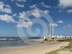 Lighthouse in the beach with cloudly day and blue sky. Ocean calm water