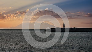 Lighthouse and beach with clouds on sunset at the port with island and mountain view