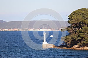 Lighthouse and a boat sailing on a calm blue sea on a sunny day