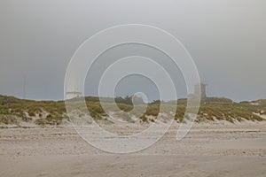 Lighthouse and bunker in the sand dunes on the beach of Blavand in fog, Jutland Denmark Europe