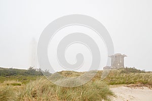 Lighthouse and bunker in the sand dunes on the beach of Blavand in fog, Jutland Denmark Europe