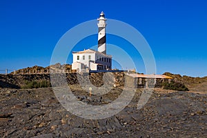 The lighthouse at Cape Favaritx amid dark slate rock, Menorca, Spain photo