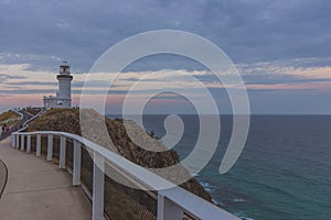 Lighthouse on cliff against cloudy sky