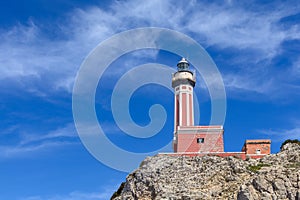 Lighthouse on a cliff in day time. Horizontal image with red and