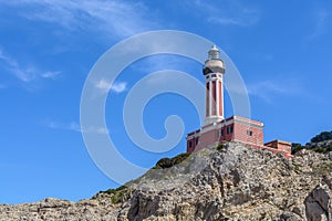 Lighthouse on a cliff in day time. Horizontal image with red and