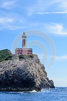 Lighthouse on a cliff in day time. Vertical image with red and w