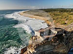 Lighthouse on a cliff rock with giant waves. ocean or sea. Aerial drone view.