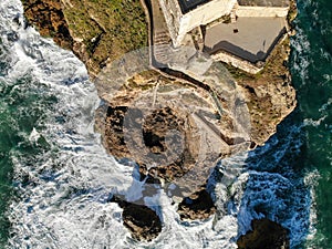 Lighthouse on a cliff rock with giant waves. ocean or sea. Aerial drone view.