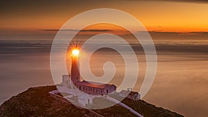 Lighthouse on coastal island with horizon and beautiful sunset