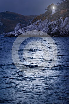 Lighthouse in the dark glows and show the rocks