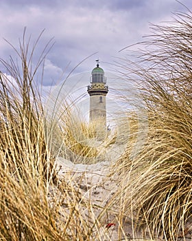 Lighthouse between dune grass. Rostock, WarnemÃÂ¼nde, Germany photo