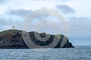 Lighthouse on ElliÃ°aey (ELLIDAEY) Island, with basalt cliffs on BreidafjÃ¶rdur Bay
