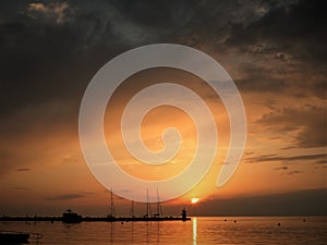 Lighthouse at the end of the pier of stones, sunset over the Adriatic Sea, Croatia, Europe.Orange, calm sea, silhouette, reflectio