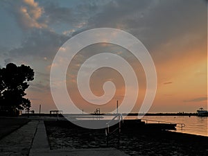 Lighthouse at the end of the pier of stones, sunset over the Adriatic Sea, Croatia, Europe.Orange, calm sea, silhouette, reflectio