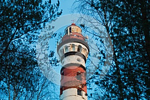 Lighthouse in the forest between the trees. red and white lighthouse