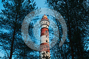 Lighthouse in the forest between the trees. red and white lighthouse
