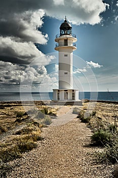 Lighthouse on the Formentera island, Spain, the blue sky with white clouds, without people, rocks, stones, sunny weather photo