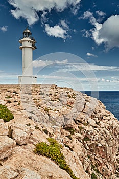 Lighthouse on the Formentera island, Spain, the blue sky with white clouds, without people, rocks, stones, sunny weather photo