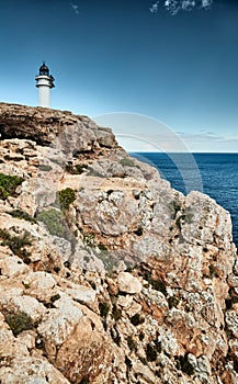 Lighthouse on the Formentera island, Spain, the blue sky with white clouds, without people, rocks, stones, sunny weather photo