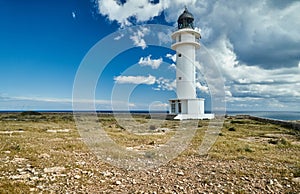 Lighthouse on the Formentera island, Spain, the blue sky with white clouds, without people, rocks, stones, sunny weather photo