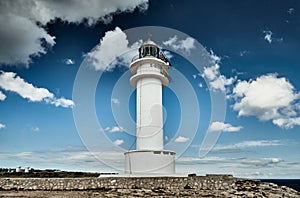 Lighthouse on the Formentera island, Spain, the blue sky with white clouds, without people, rocks, stones, sunny weather photo