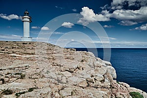 Lighthouse on the Formentera island, Spain, the blue sky with white clouds, without people, rocks, stones, sunny weather photo
