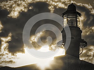 Lighthouse green beacon against cloudy sky