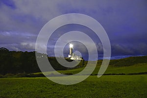 Lighthouse illuminated at dusk over blue sky
