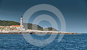 The lighthouse on the island in Croatia nearby Vis at sunset, a rocky coast, ladder to a beacon, a small cape