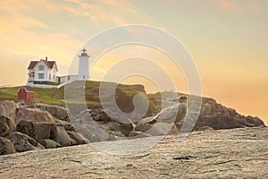 Lighthouse on an island in the ocean at dawn. A seagull on the coastal rocks and a lighthouse . USA. Maine. Nubble Lighthouse