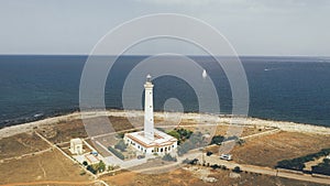 Lighthouse at island\'s coastline with sailboat in the background