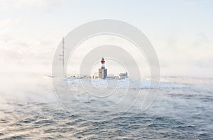 Lighthouse on an isle in misty sea photo