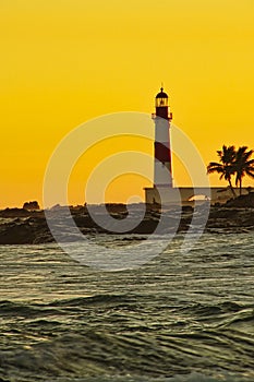 Lighthouse Itapua beach with yellow sky at sunset, Salvador, Bahia, Brazil
