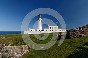 Lighthouse and keepers house on grassy hillside along the sea