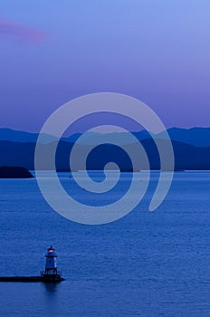 Lighthouse on Lake Champlain at dusk with Adirondack mountains in background