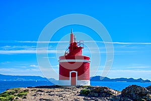 Lighthouse In Landscape. The iconic red lighthouse at Punta Robaleira. Cabo Home, Cangas, Galicia, Spain photo