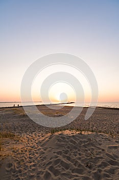 Lighthouse during a last minute of sunset with a big sun close to the horizon and clear sky