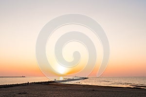 Lighthouse during a last minute of sunset with a big sun close to the horizon and clear sky