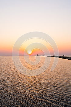 Lighthouse during a last minute of sunset with a big sun close to the horizon and clear sky