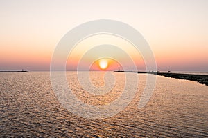 Lighthouse during a last minute of sunset with a big sun close to the horizon and clear sky