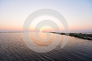 Lighthouse during a last minute of sunset with a big sun close to the horizon and clear sky