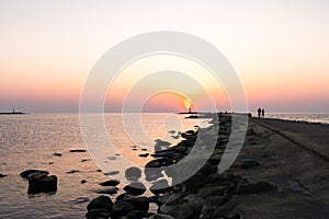 Lighthouse during a last minute of sunset with a big sun close to the horizon and clear sky