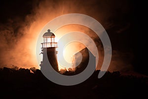 Lighthouse with light beam at night with fog.
