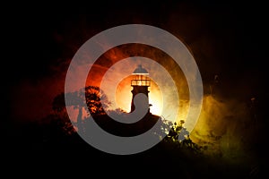 Lighthouse with light beam at night with fog. Old lighthouse standing on mountain. Table decoration. Selective focus