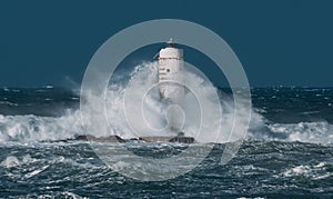 The lighthouse of the Mangiabarche shrouded by the waves of a mistral wind storm