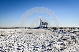 The lighthouse of Marken, `het Paard van Marken` in winter and the frozen Markermeer, Holland