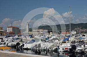 Lighthouse, motor boats and sailboats in harbor in Trieste, Ital